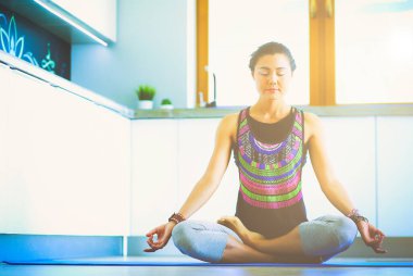 Genç kadın lotus pozisyonunda evde Yoga yapıyor. Yoga. Kadın. Yaşam tarzı.