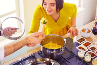 Evdeki mutfakta birlikte yemek pişiren çift..