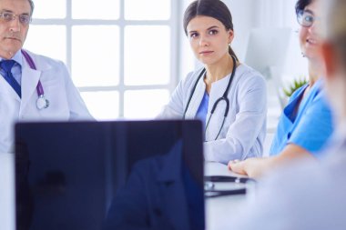 Ciddi bir tıbbi ekip parlak bir ofiste dizüstü bilgisayar kullanıyor.