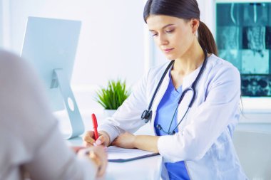 Doktor ve hasta acil serviste resepsiyon masasının yanında dururken bir şey tartışıyorlar.