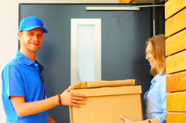 Mavi üniformalı gülümseyen kurye servis konseptine paket kutusu teslim eden teslimatçı. Mavi üniformalı gülümseyen teslimatçı..