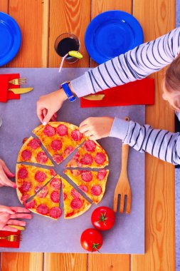 Ahşap masada otururken birlikte yemek yiyen bir grup insanın üst düzey görüntüsü. Masada yemek var. İnsanlar fast food yiyor.