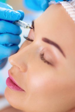 Kaşlar için kalıcı makyaj. Güzellik salonunda kalın kaşlı güzel bir kadın..