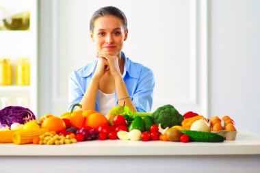 Ahşap iç kısımda meyve ve sebze dolu masada oturan genç ve tatlı bir kadın..