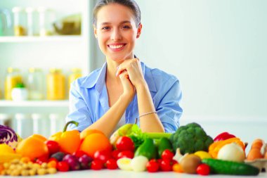 Ahşap iç kısımda meyve ve sebze dolu masada oturan genç ve tatlı bir kadın..