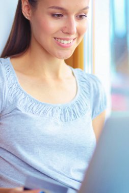 Evde bir dizüstü bilgisayar kullanan genç güzel kadın. Genç güzel kadın