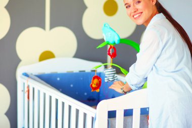 Çocuk karyolası duran genç kadın. Genç anne.