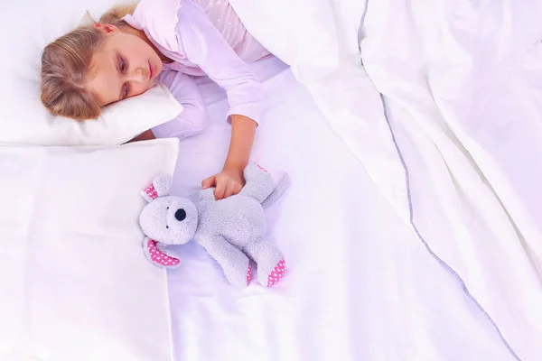 stock image Child little girl sleeps in the bed with a toy teddy bear