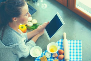 Tablette tarifi takip eden bir kadın evde yemek pişiriyor..