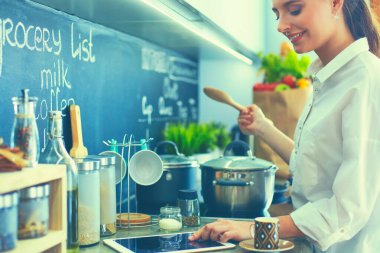 Mutfakta sobanın yanında duran genç bir kadın. .