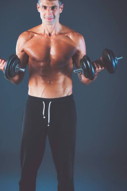 Yakışıklı kaslı adam dumbell ile çalışma dışarı. Kişisel fitness eğitmeni. Kişisel eğitim