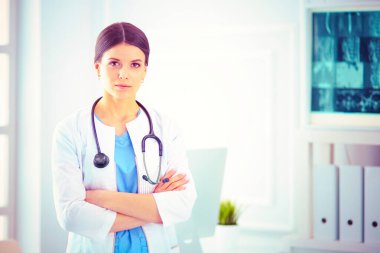 Doktor muayenehanesinde steteskopla gülümseyen genç bayan doktor.