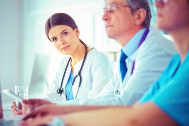 Ciddi bir tıbbi ekip parlak bir ofiste dizüstü bilgisayar kullanıyor.