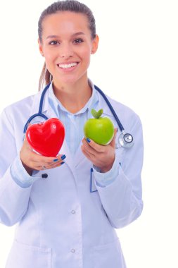 Güzel gülümseyen kadın doktor kırmızı kalp ve yeşil elma tutuyor. Kadın doktor
