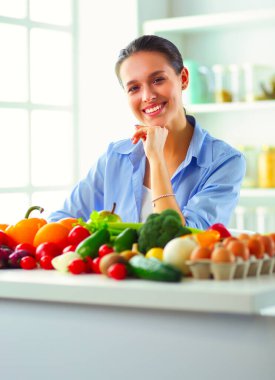 Ahşap iç kısımda meyve ve sebze dolu masada oturan genç ve tatlı bir kadın..