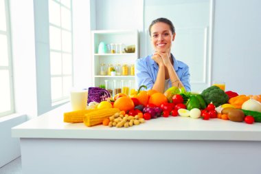 Ahşap iç kısımda meyve ve sebze dolu masada oturan genç ve tatlı bir kadın..