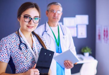 Bir doktor ekibi, kadın ve erkek, ofiste bekliyorlar..