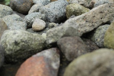 Nehir kıyısındaki doğal kayalar. Çakıl taşları ve renkli çakıl taşları yakın plan sularda. Nehir kıyısında değişik boyutlarda taşların dokusu.