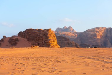 Ürdün, Wadi Rum - 2 Kasım 2022 Çölde develerin karavanı, gün batımında kaya dağları