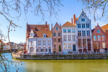 Bruges, Belgium - April 10, 2016: Bruges, Belgium canal and colorful traditional houses against cloudy blue sky in popular belgian destination, Brugge