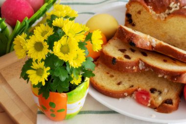 Easter background with yellow flowers, colorful painted eggs and holiday cake still-life
