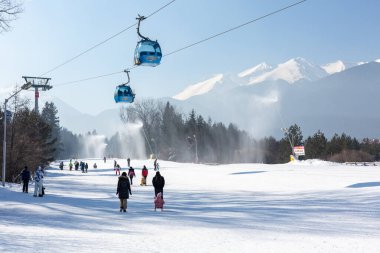 Bansko, Bulgaria - February 11, 2023: Bulgarian winter ski resort panorama with gondola lift cabins, Pirin mountain peaks view and slope