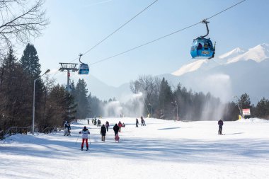 Bansko, Bulgaria - February 11, 2023: Bulgarian winter ski resort panorama with gondola lift cabins, Pirin mountain peaks view and slope