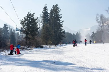 Bansko, Bulgaria - February 11, 2023: Bulgarian winter ski resort panorama with gondola lift cabins, Pirin mountain peaks view and slope
