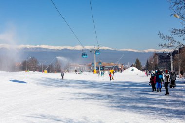 Bansko, Bulgaria - February 11, 2023: Bulgarian winter ski resort panorama with gondola lift cabins, Rila mountain peaks view and slope
