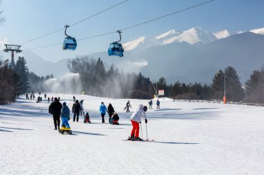 Bansko, Bulgaria - February 11, 2023: Bulgarian winter ski resort panorama with gondola lift cabins, Pirin mountain peaks view and slope