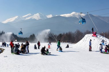 Bansko, Bulgaria - February 11, 2023: Bulgarian winter ski resort panorama with gondola lift cabins, Pirin mountain peaks view and slope