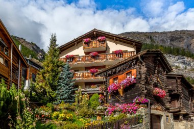 Yazın penceresinde sardunya çiçekleri olan geleneksel tahta dağ evi, Zermatt alp köyü, İsviçre, İsviçre Alpleri