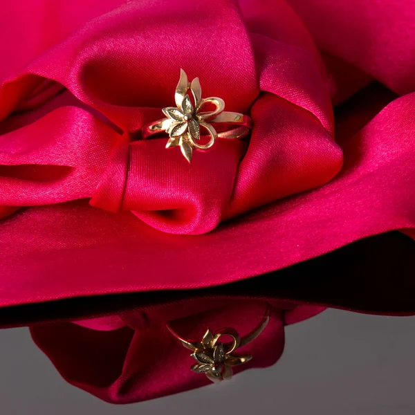 stock image Gold ring in shape of flower leaves jewellery on red silk, copy space