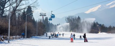 Bansko, Bulgaria - February 11, 2023: Bulgarian winter ski resort panorama with gondola lift cabins, Pirin mountain peaks view and slope