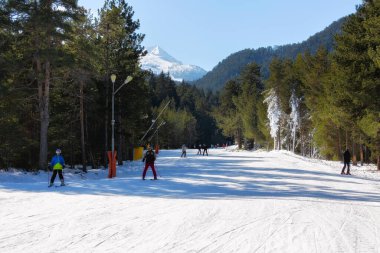 Bansko, Bulgaristan - 11 Şubat 2023: Kayak yolu ve kayakçılarla ünlü tatil beldesi ve Todorka zirvesinde kış manzarası