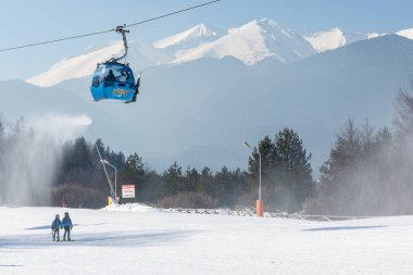 Bansko, Bulgaria - February 11, 2023: Bulgarian winter ski resort panorama with gondola lift cabins, Pirin mountain peaks view and slope