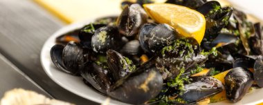 Beyaz şarap soslu haşlanmış midye ve tabakta limon.