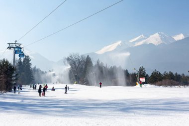 Bansko, Bulgaria - February 11, 2023: Bulgarian winter ski resort panorama with gondola lift cabins, Pirin mountain peaks view and slope