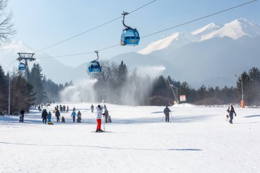 Bansko, Bulgaria - February 11, 2023: Bulgarian winter ski resort panorama with gondola lift cabins, Pirin mountain peaks view and slope
