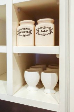 Rafta tuz ve biber beyaz seramik kavanozlar ve yumurta tutacakları var.