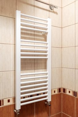 Tuvalet için beyaz elektrikli havlu kurutma makinesi fayanslı bir duvara monte edilmiş.