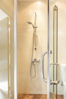 Duş kabini, içinde bej duvarlar olan banyo.