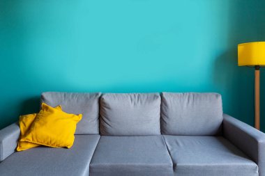 Lüks oturma odası şablonu modern iç tasarım, turkuaz boş duvar, gri kanepe, sarı lamba ve yastıklar.