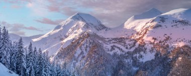 Pirin, Bulgaristan 'da kış tatili. Karla kaplı dağ zirveleri ve bulutlu gün batımı gökyüzü ile panoramik arka plan.