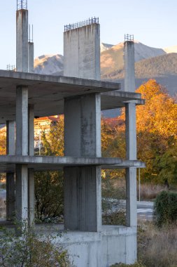 Terk edilmiş inşaat, tamamlanmamış çerçeve, Bulgaristan 'ın Bansko kentinde güçlendirilmiş beton bina, arkasında Pirin dağları