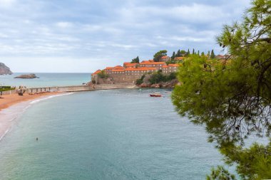 Karadağ 'daki Sveti Stefan adası Adriyatik denizi, çam ağacı ve sahil manzaralı tatil beldesi