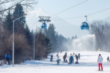 Bansko, Bulgaria - February 11, 2023: Bulgarian winter ski resort panorama with gondola lift cabins, Pirin mountain peaks view and slope