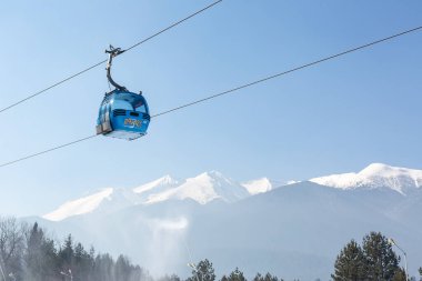 Bansko, Bulgaria - February 11, 2023: Bulgarian winter ski resort panorama with gondola lift cabin, Pirin mountain peaks view