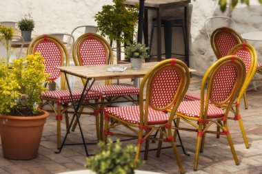 Açık hava boş kahve ve restoran terasında kırmızı ve beyaz sandalyeler ve masa, çiçekler.