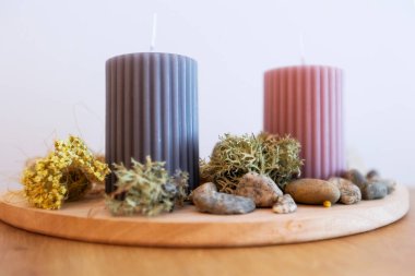 Masanın üzerinde iki mum, ahşap tutacağı taşlı ve yosunlu süsleme.